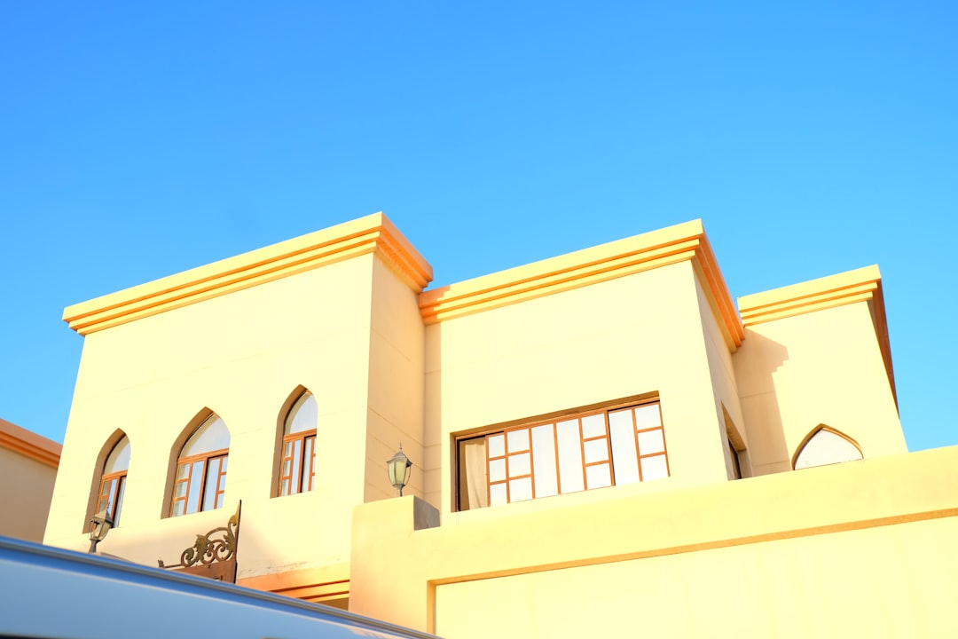 a-white-van-parked-in-front-of-a-yellow-building-wmuxxfnfjxo