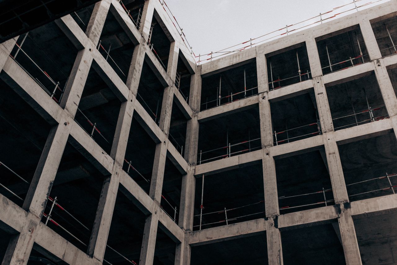 A low angle view of a modern concrete building under construction, showcasing its structure and design.